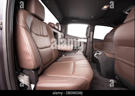 Bequeme Ledersitze hinten und offener Getränkehalter im Fahrzeuginnenraum mit isolierten Fenstern Stockfoto