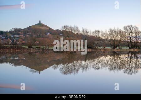 Ein Blick auf Glastonbury Tor im Winter am frühen Morgen von der Kuhbrücke über überflutete Felder von Lower Actis. Glastonbury, Somerset, England, Großbritannien Stockfoto