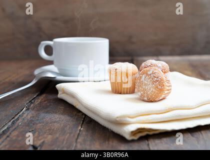 Muffins mit Kaffeetasse auf Holztisch Stockfoto