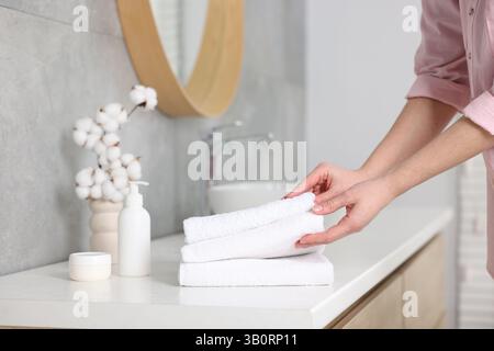Frau, die saubere Handtücher vom Waschtisch im Bad nahm, Nahaufnahme Stockfoto