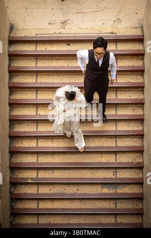 Ein junges Paar steigt vom Dach des Dong Xuan Markts ab, nachdem es Hochzeitsfotos gemacht hat. Hanoi, Vietnam Stockfoto