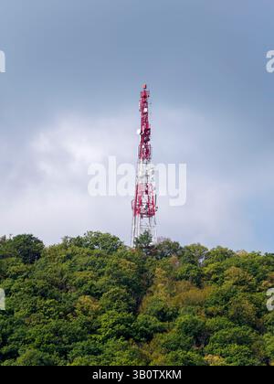 Direktionales Antennenarray auf einem rot-weißen Kommunikationsturm gegen den Himmel. Stockfoto