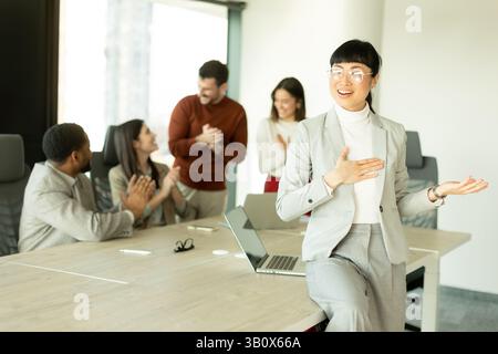 Eine Gruppe verschiedener Fachleute führte in einem sonnendurchfluteten Büro lebhafte Diskussionen. Eine Frau steht selbstbewusst und zeigt Teamarbeit und Zusammenarbeit i Stockfoto