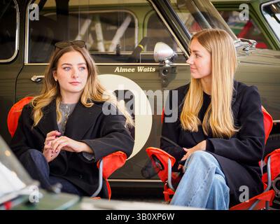 Zwei attraktive Frauen sitzen im Fahrerlager beim 82 Members Meeting, Goodwood Motor Circuit, West Sussex UK Stockfoto