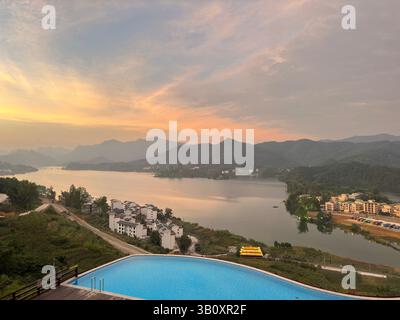 Ein atemberaubender Sonnenuntergang zeigt den Himmel über einem ruhigen See und einer Bergkette in Guangxi, China. Stockfoto
