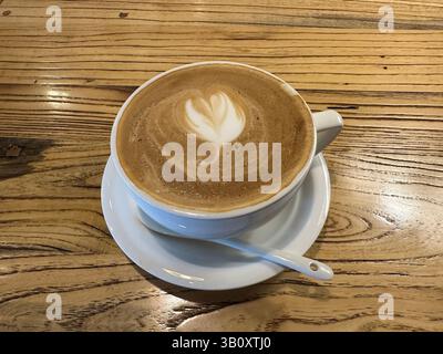 Ein wunderschön gefertigter Latte, komplett mit Herzdesign, bereit, im Café zu genießen. Stockfoto