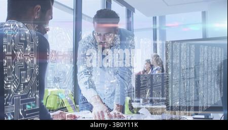 Bildschirme mit Mikroprozessoranschlüssen gegen zwei verschiedene männliche Kollegen, die im Büro diskutieren Stockfoto