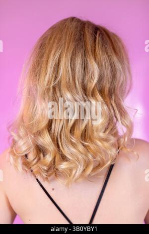 Ein elegantes, fesselndes Porträt mit atemberaubendem blondem, lockigem Haar von der Rückseite Stockfoto