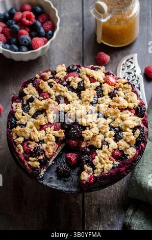 Gemischte Beerenstreuseltorte auf hölzernem Hintergrund Stockfoto