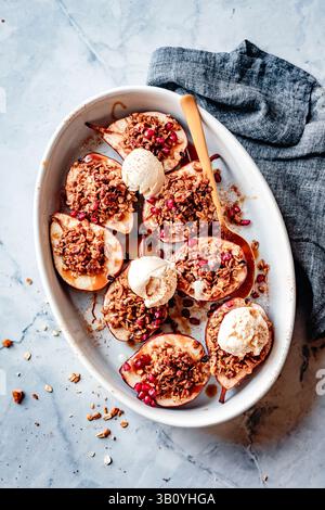Gebackene Birnen mit Granola-Streusel und Eis, serviert auf einem weißen ovalen Gericht. Stockfoto