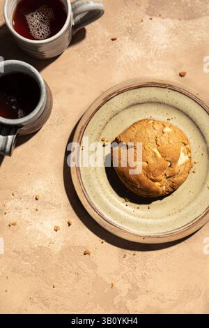 Grober weißer Schokoladenkeks auf einem Teller mit zwei Kaffeetassen. Stockfoto