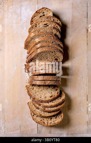Frischer Sauerteigbrot in Scheiben auf hölzernem Hintergrund angeordnet. Rustikales hausgemachtes Brot mit knuspriger Kruste und weicher Innenstruktur. Stockfoto