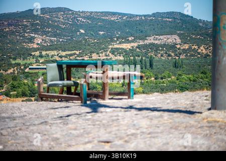 Eine friedliche Anordnung von Tischen und Stühlen in der Nähe einer üppigen Naturlandschaft, ideal zum Entspannen, Essen oder Genießen der Aussicht. Stockfoto