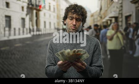 Der hispanische Mann zählt tschechische Kronen-Banknoten auf der Straße draußen, die ein Finanzkonzept zeigen. Stockfoto