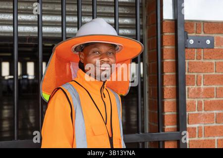 afrikanischer Mann Arbeiter draußen trägt Sonnenschirm harte Hut volle Krempe Hals Sonnenschirm mit reflektierendem Streifen Stockfoto