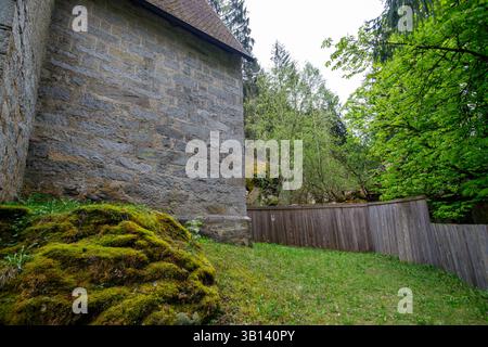 Bad Illstern, italien, verlor seinen Platz. Außenaufnahme einer Steinbauecke mit moosbewachsener Bodenabdeckung, neben einem Holzzaun und Wald. Stockfoto