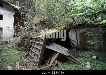 Bad Illstern, italien, verlor seinen Platz. Baufällige Gebäude, eines teilweise eingestürzt, sitzen inmitten üppig grüner Vegetation und bewachsener Vegetation in einem Zustand von A Stockfoto
