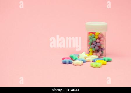 Detaillierte Abbildung von Behältern mit dekorativen Elementen in Form von Sternen und Blumen, platziert auf einem rosafarbenen Hintergrund. Stockfoto