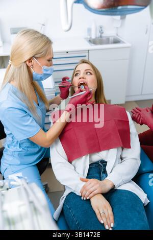 Zahnarzt untersucht, Zahnarzt untersucht Zahn, Zahninstrumente, Untersuchungspatient, Zähne überprüfen, Zahnarzt zeigt, professioneller Arzt, der Zähne repariert, Stockfoto