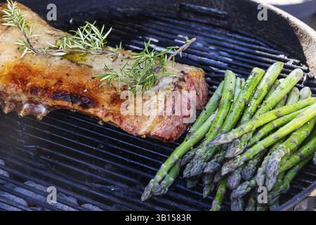 Barbecue mit Osterbraten. Lammrücken und grüner Spargel auf einem Wasserkocher Grill im Freien gegrillt. Fleisch und vegetarisches Gemüse. Baden-Württemberg Stockfoto