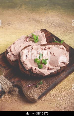 Leberpastete, auf Getreidebrot aufgetragen, auf einem Schneidebrett, Frühstück, Nahaufnahme, ohne Menschen, selektiver Fokus Stockfoto