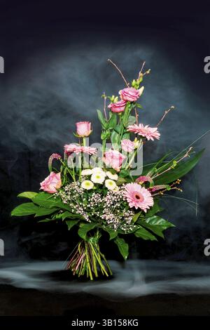Farbenfroher Blumenstrauß auf schwarzem Hintergrund mit Nebeleffekt Stockfoto
