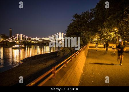 London, Großbritannien - 14. September 2023: Am späten Abend im Battersea Park, wo Leute laufen und laufen und einen Blick auf die Chelsea Bridge in der Ferne haben. Stockfoto