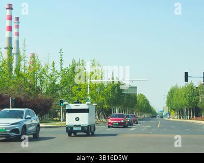 Autonomes Lieferfahrzeug im Stadtverkehr unter Elektroautos in der modernen chinesischen Stadt Shandogn, China Stockfoto