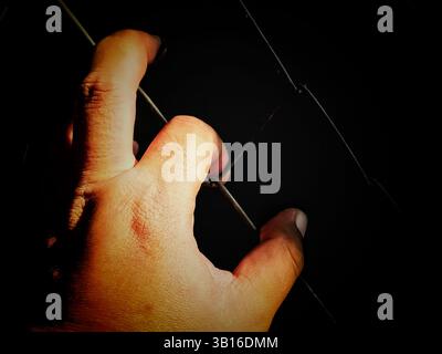 Hände, die einen Käfig halten, ein Konzept, eingesperrt und frei zu sein, ein Gefangener, der zu Gefängnisstrafen verurteilt wird. Stockfoto