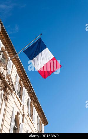 Französische Flagge fliegt am Fahnenmast im Hintergrund des blauen Himmels, Arles, Bouches du Rhône, Frankreich Stockfoto