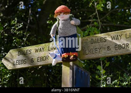 Yarnbombe Person am Fingerpfosten befestigt (öffentlicher Fernwanderweg, Ebor Way, Dales Way Link) Nahaufnahme - Menston, West Yorkshire, England Großbritannien. Stockfoto