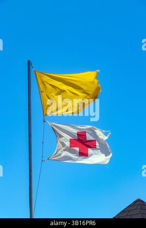 Rotes Kreuz und gelbe Flagge vor blauem Himmel am Strand teneriffas, Warnung vor gefährlichen Badegebieten des Meeres und Rettungsschwimmer im Dienst Stockfoto