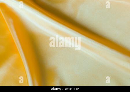 Goldenes Seidentuch mit seidenem Glanz und wunderschönen Naturdrapierungen. Stockfoto