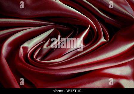 Blick von oben auf poliertes dunkelrotes Seidentuch mit seidenweichem Glanz und wunderschönen natürlichen Vorhängen. Geeignet für Design und Hintergrundtapeten. Stockfoto