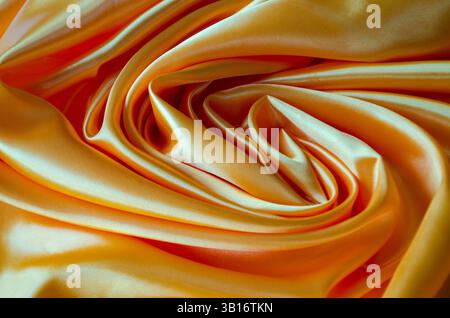 Blick von oben auf poliertes goldenes Seidentuch mit seidenem Glanz und wunderschönen natürlichen Vorhängen. Geeignet für Design und Hintergrundtapeten. Stockfoto
