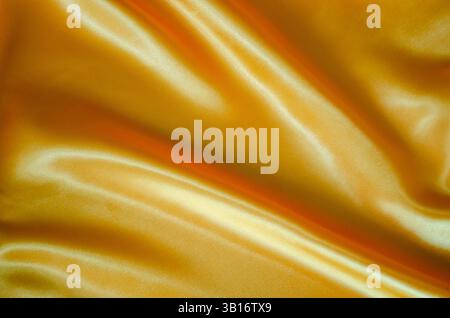 Blick von oben auf goldgelbes Seidentuch mit seidenem Glanz, geeignet für Design und Tapetenhintergrund. Stockfoto