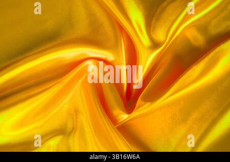 Goldgelbe Seide mit weichen Kurven und leuchtender reflektierender Oberfläche. Geeignet für Design und Hintergrundtapeten. Stockfoto
