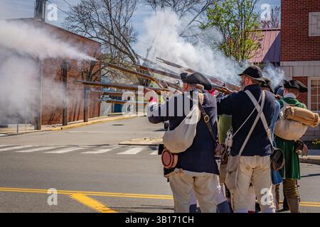Arlington, MA, USA-20. April 2025: Battle of Menotomy 250th Reenactment – patriotische Kolonialisten kämpfen gegen britische Soldaten auf der Massachusetts Avenue. Stockfoto