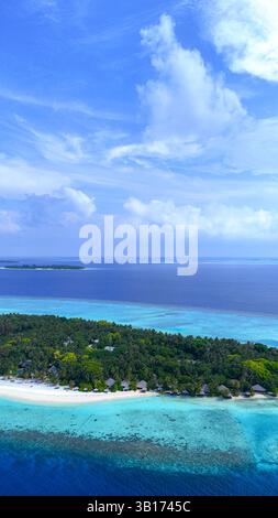 Tropische Insel der Malediven aus der Vogelperspektive umgeben von türkisfarbenem Meer, hellem Tageslicht und üppigem Grün, Sommerurlaub, Reisebüro, Hotelresort Stockfoto