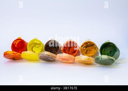 Nahaufnahme von sechs geöffneten Plastikgläsern mit Grün, Senf, Orange, Braun, Gelb, und rote, trockene Gouachefarben Stockfoto