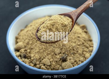 Bio Brown Sugar: Eine Nahaufnahme fängt die reichhaltige Textur und das einladende Aroma von Bio-braunem Zucker ein, präsentiert in einer rustikalen Schüssel und einem Holzlöffel. Stockfoto