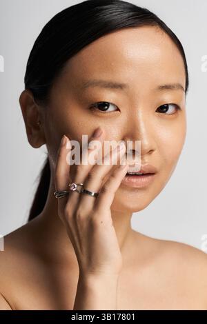Eine junge asiatische Frau berührt ihr Gesicht und unterstreicht ihre Schönheit und ihr Selbstvertrauen. Stockfoto