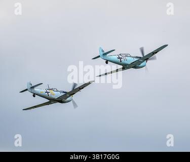 Zwei Messerschmitt Bf 109 Kampfflugzeuge in Formation gegen bewölkten Himmel während einer Flugshow in Duxford, England. Stockfoto