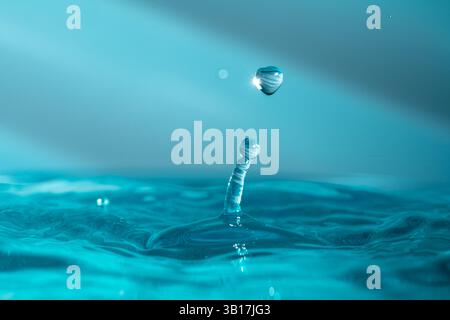 Wassertropfen fallen dicht in das blaue Wasser, was es zum perfekten Zentrum in der Natur macht Stockfoto