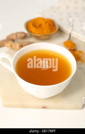 Aromatischer Kurkuma-Tee, Pulver und Rhizome auf weißem Tisch, Nahaufnahme Stockfoto