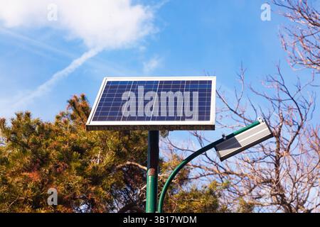 Ein Solarmodul ist an einer Straßenlaterne in einem Park installiert. Stockfoto