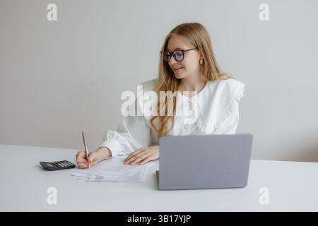 Professionelle Frau, die tagsüber an einem Schreibtisch in einem modernen Büro an Finanzdokumenten arbeitet Stockfoto