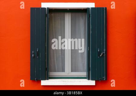 Grüne Fensterläden an einer leuchtend roten Wand Stockfoto