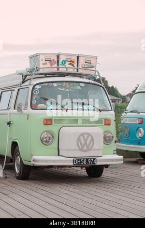 Vintage Volkswagen California Wohnmobil mit Surfbrettern auf dem Dach, das an der Küste geparkt ist, repräsentiert Retro-Surfkultur und Abenteuerreisen. Stockfoto