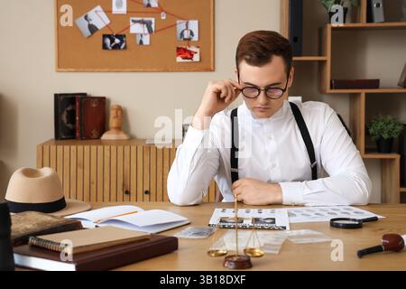 Männlicher Detective mit Fingerabdrücken, der den Fall am Tisch im Büro untersucht Stockfoto